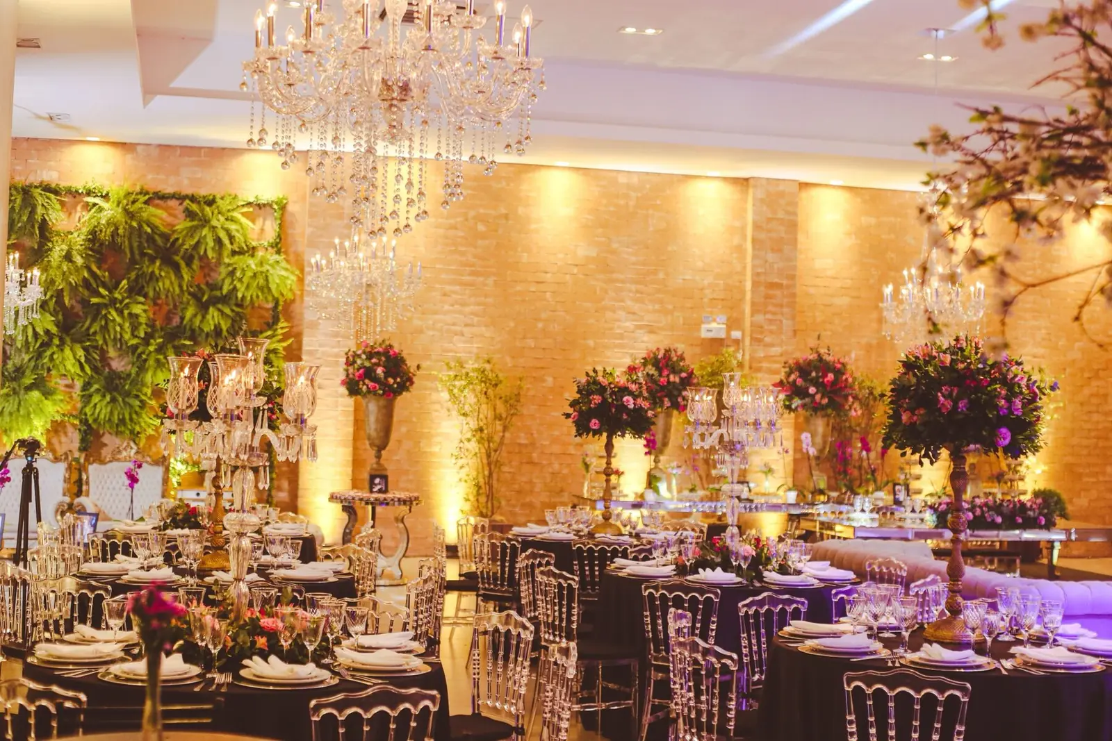 Champagne uplighting on brick walls in a reception room with chandeliers
