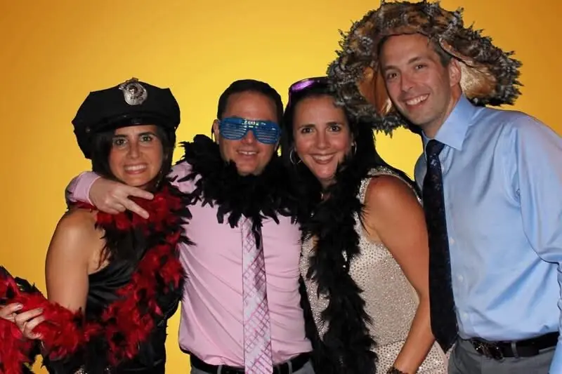 Four guests in feather boas and party props at a photo booth